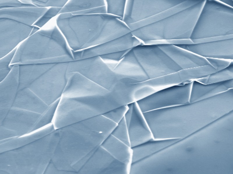 Graphene nanofabric. SEM micrograph of a strongly crumpled graphene sheet on a Si wafer. Note that it looks just like silk thrown over a surface. Lateral size of the image is 20 microns. Si wafer is at the bottom-right corner.