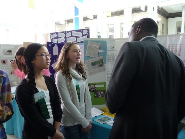 Young students talk to a judge at a science fair