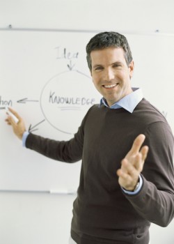close-up of a teacher pointing towards a whiteboard
