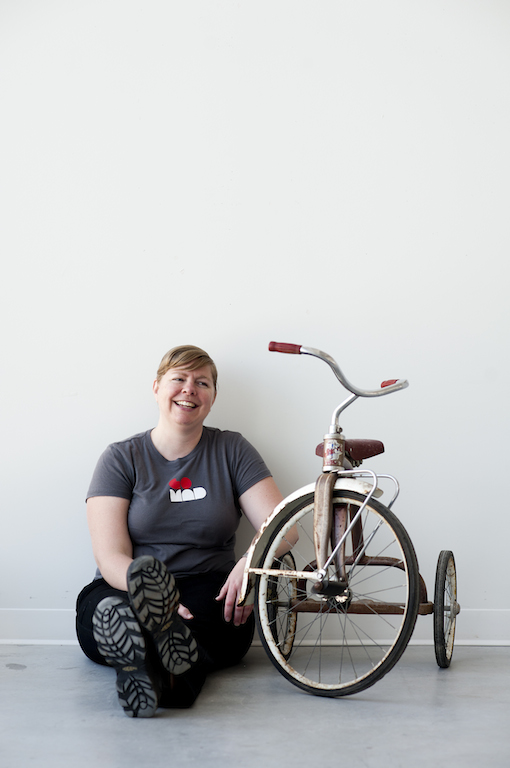 Carolyn Mount sits next to an old tricycle she traded for her art. Her thesis explores alternative economies: Throughout one year, she is either giving or trading all the work she makes. / Photo: Katie Chalmers-Brooks