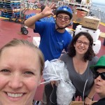 The University of Manitoba team during cruise mobilization on deck of the Amundsen in Québec City, Québec. Alexis Burt, Kang Wang, Deb Armstrong, and Kathleen Munson (left to right) unpack boxes and install equipment. // Photo by Alexis Burt