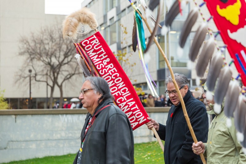 Carl Stone leading the ceremonial procession across the Fort Garry Campus