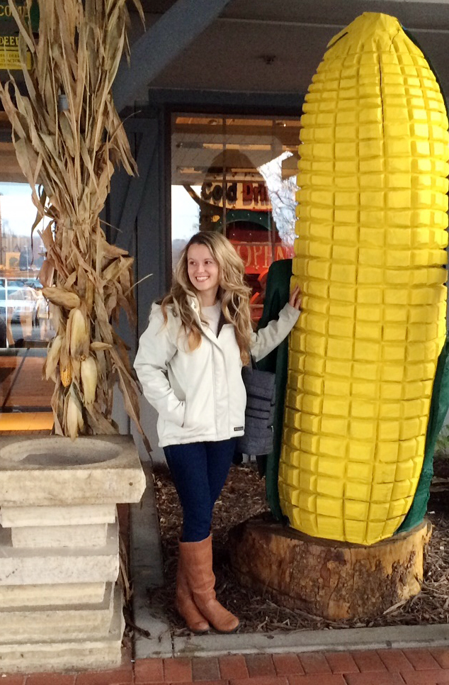 Magdalena Rogalsky next to a giant cob of corn