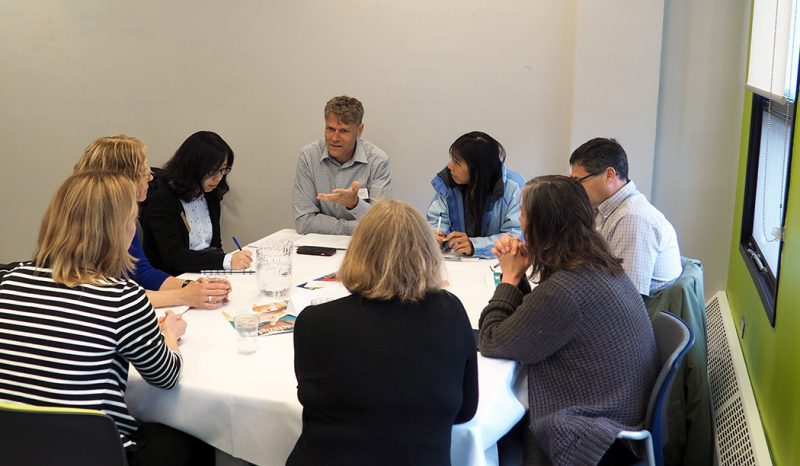 A group sits around a table listening to Nathan Greidanus as he leads a seminar at the 2017 Teaching Café.
