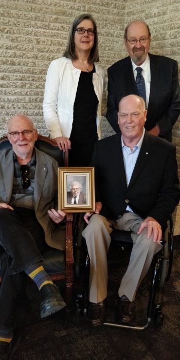 Former Deans of Law: (standing) Professors Lorna Turnbull and Trevor Anderson; (seated) Professor Jack London holding a photo of the late Roland Penner, C.M., O.M., Q.C., and Professor Art Braid.