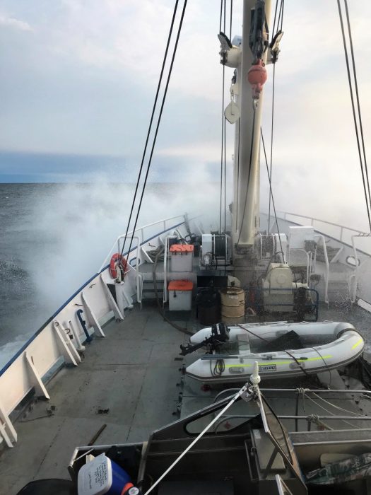 Waves crashing over the bow of the MV Namao. The entrance to the hold is one of the orange hatches on the foredeck.