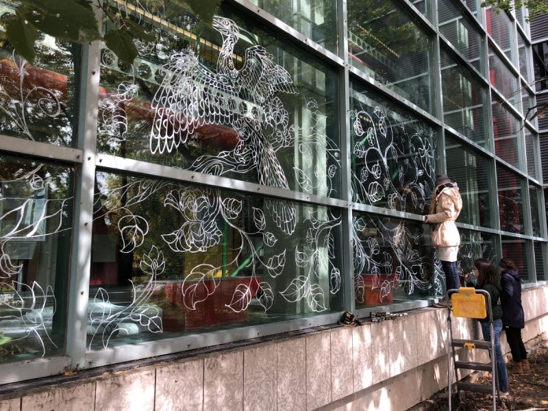 Students apply art to the windows of the Wallace building