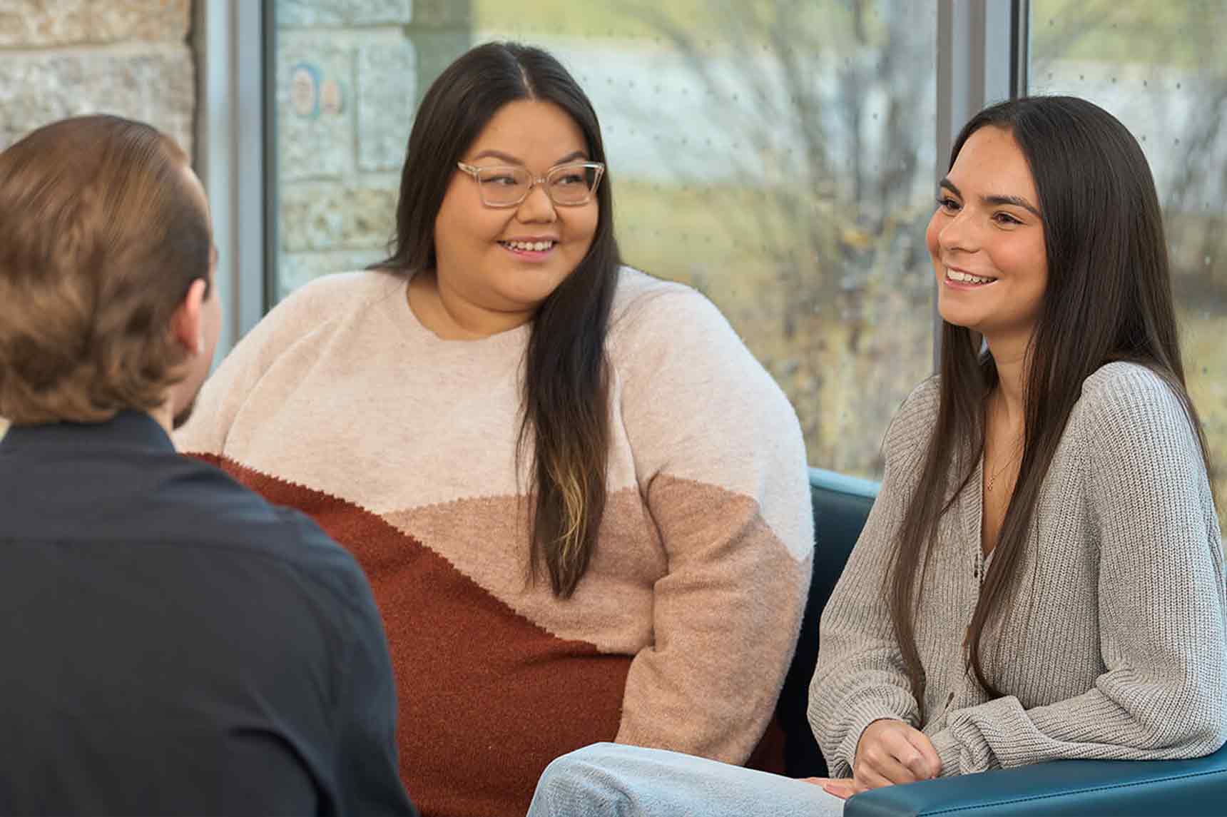 Three students sitting on sofas chatting.