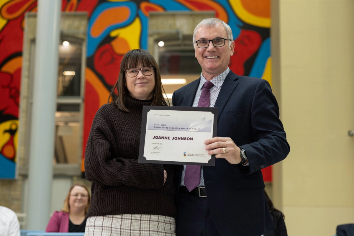 Two people smiling at the camera. Joanne Johnson, on the left, is holding a certificate.