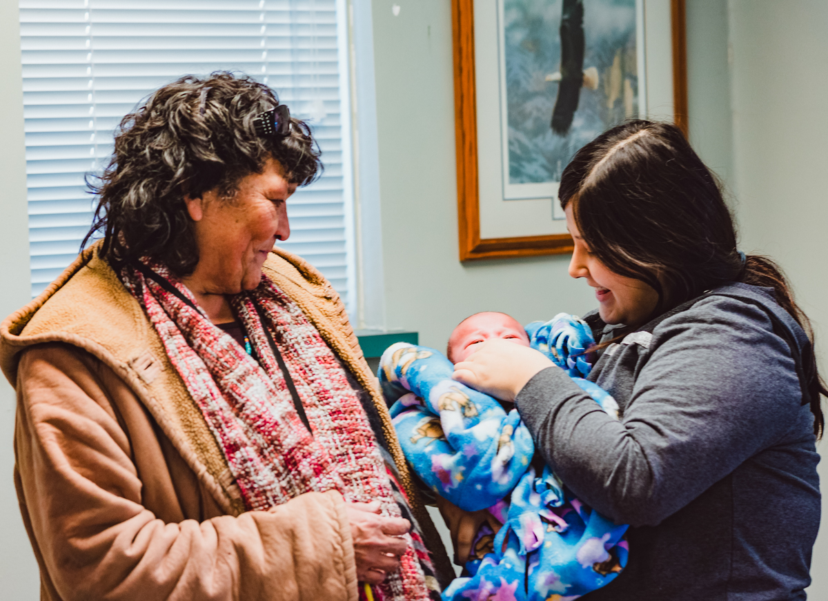 An Elder with granddaughter who is holding her baby.