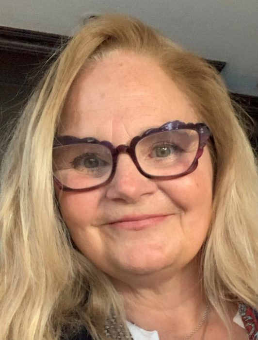 A smiling blonde woman with glasses