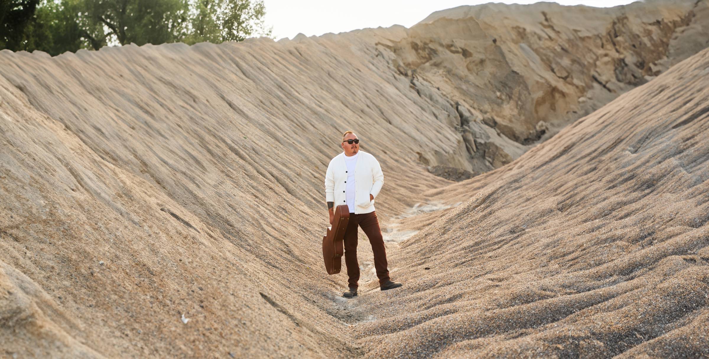 William Prince standing between two sandy hills.