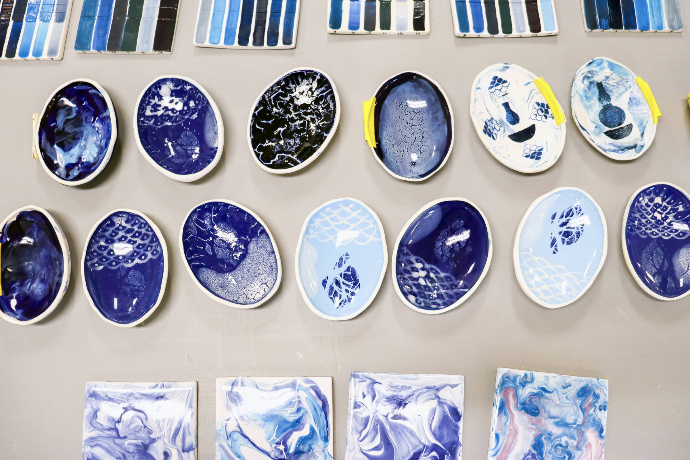 Cerics painted in various shades of blue laid out on a table.