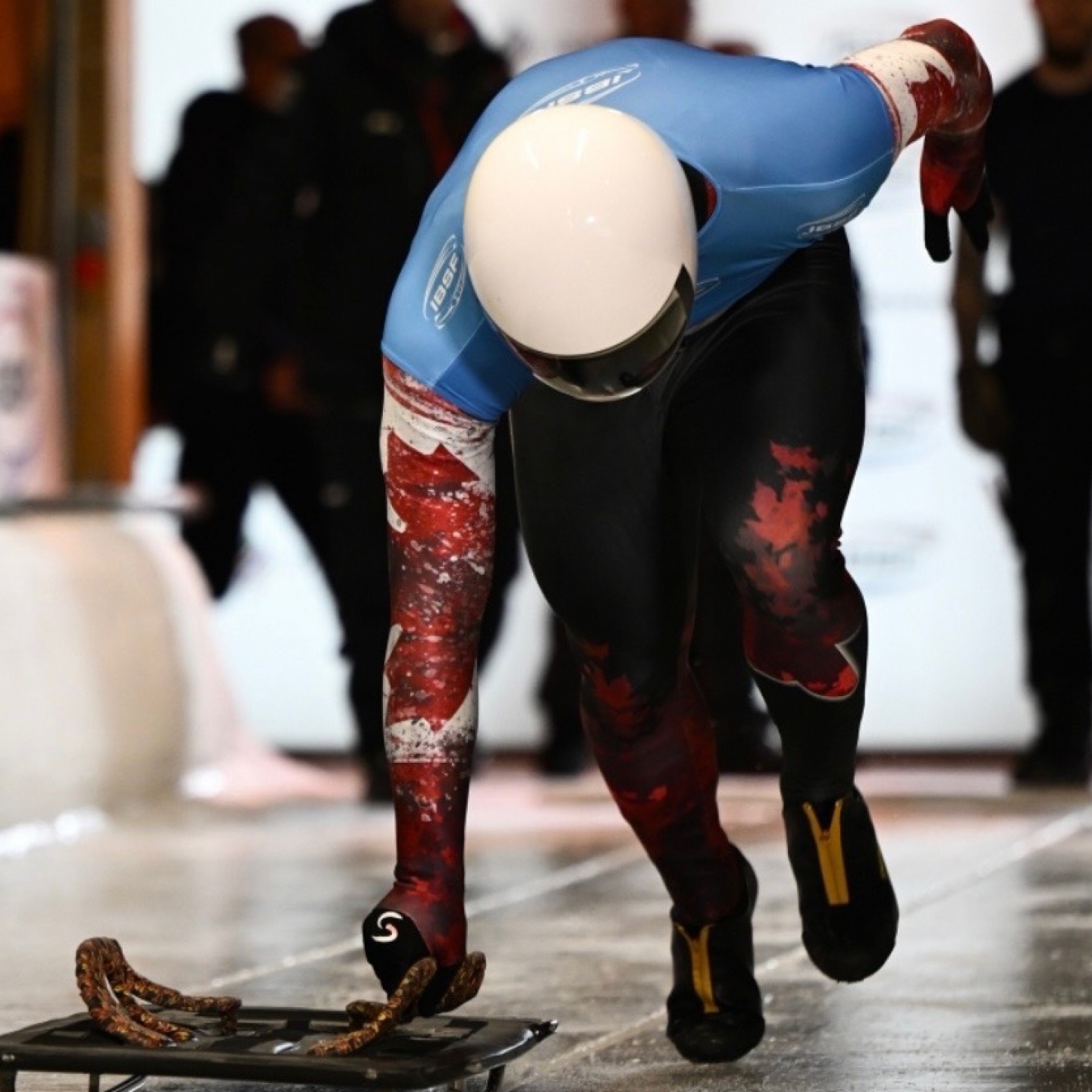 An athlete in the start chute for a skeleton race sprints toward the camera