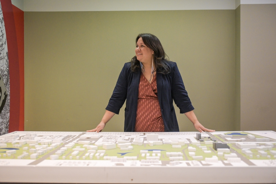 Woman with long black hair looking over a diorama 