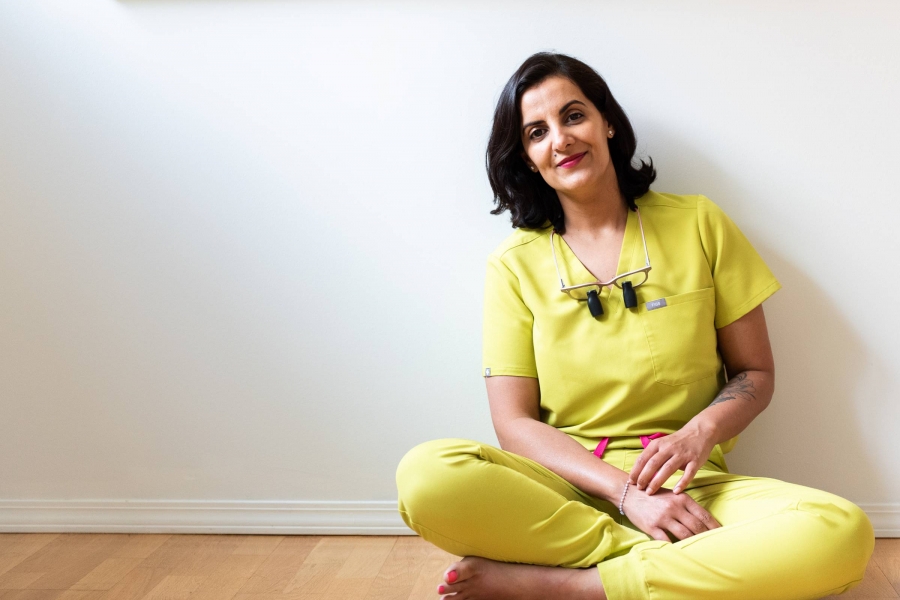 Huma Sharief sits crosslegged on the floor, leaning against the blank wall of her condo