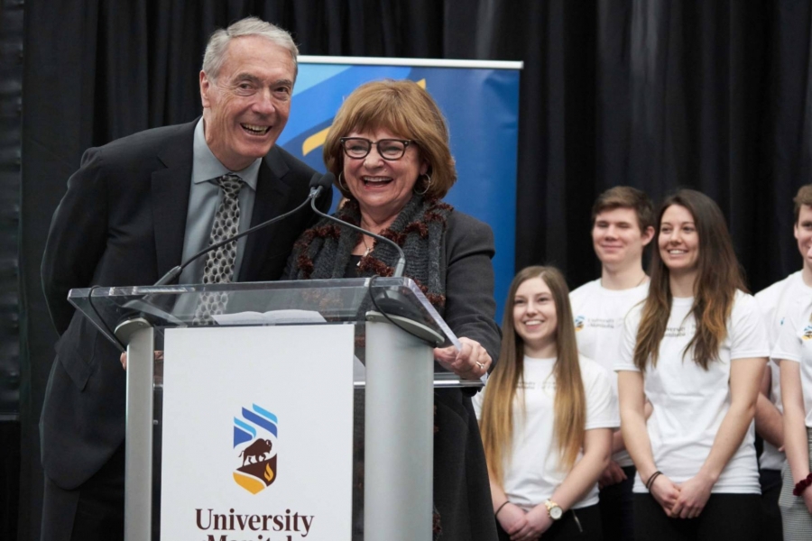 Gerry and Barb Price happily speak at a podium in front of group of students.