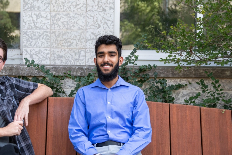 Cody McDonald and Simar Ubhi sit on a bench on UM's Fort Garry Campus