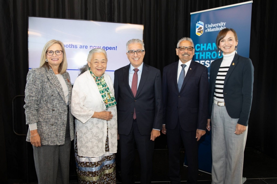 Executives from the University pose together on a stage.