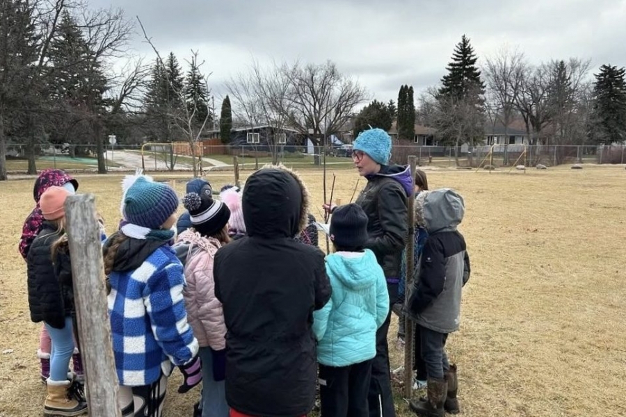 An adult stands outside with students.