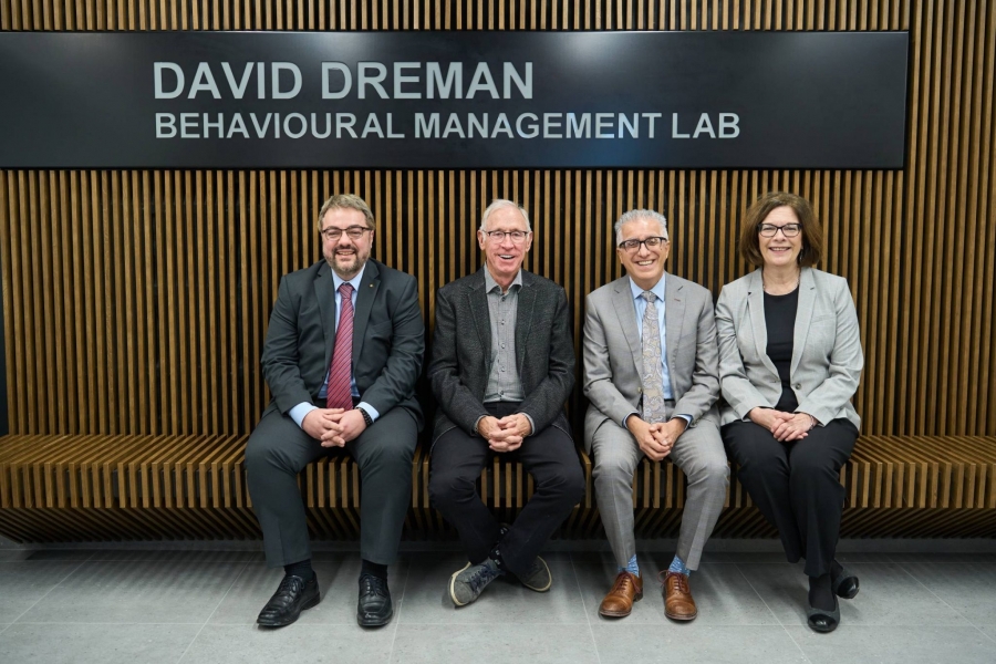 4 individuals sit in front of a sign for the David Dreman Behavioural Management Lab
