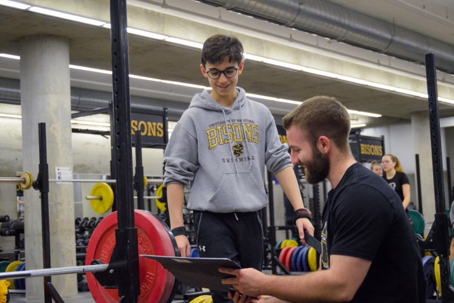 Two men in a gym with weights.