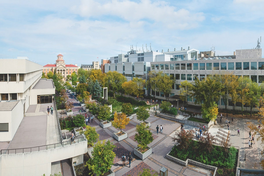 Fort Garry campus from above, showing trees, a walking path, and mid-century buildings.