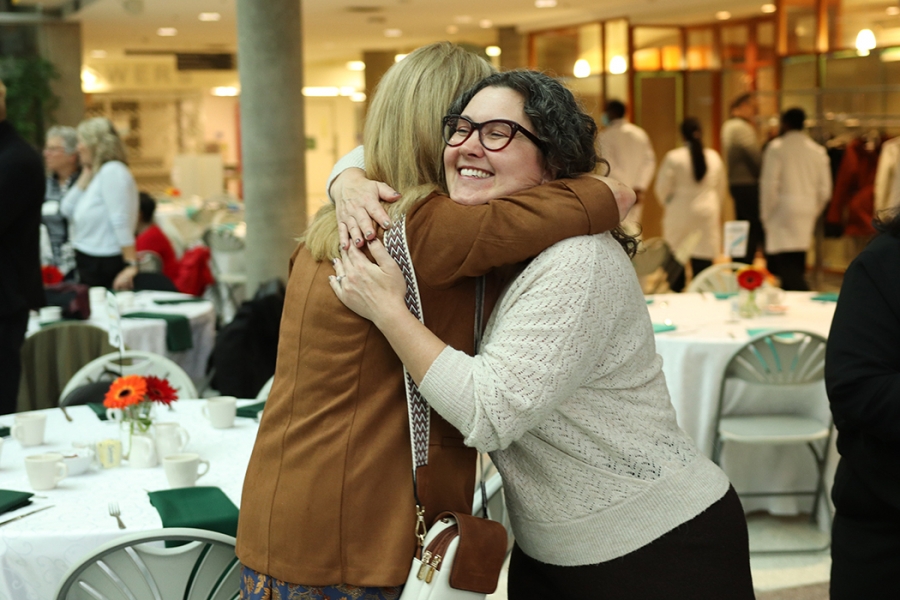 Two alumni embrace at the Dean's Homecoming Breakfast at Bannatyne campus.