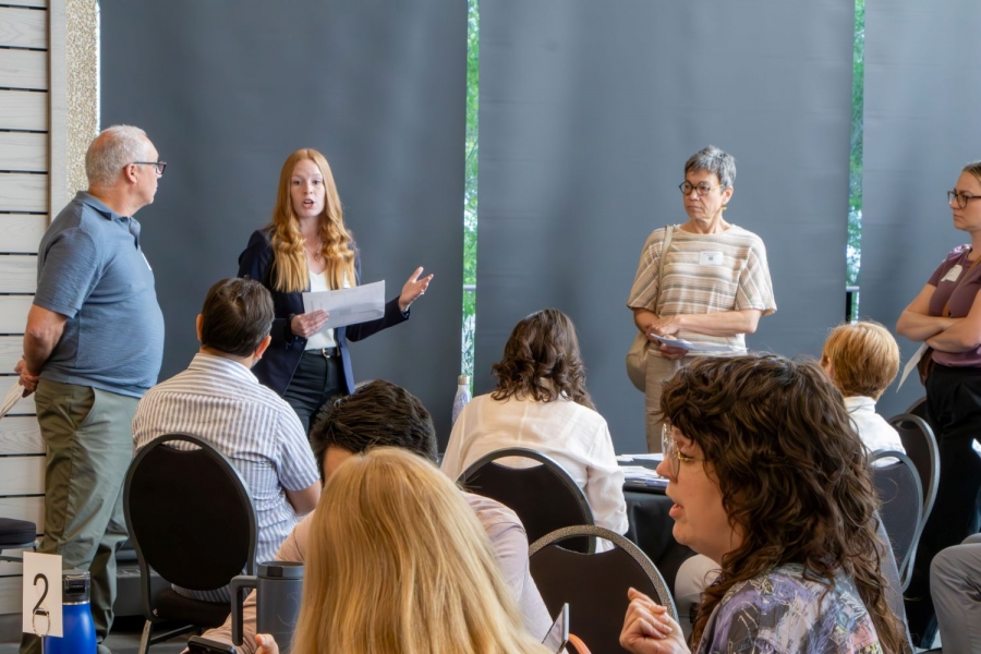 Facilitators stand in front of a group of people leading or having a discussion