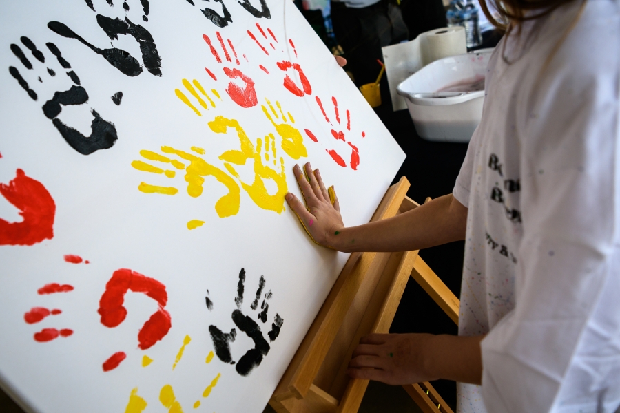 Hand prints made with paint in Indigenous colours of black, red and yellow. 
