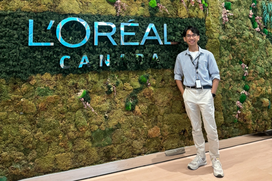 Jared Salvador smiling in front of a vertical garden wall featuring the L’Oréal Canada logo.