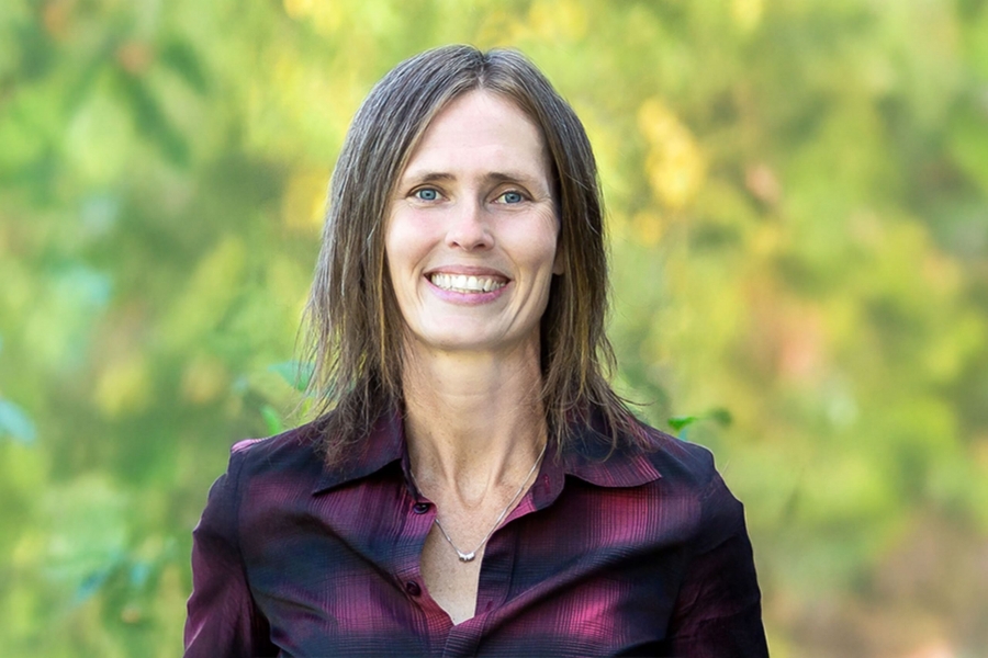 Smiling person in front of green folliage.