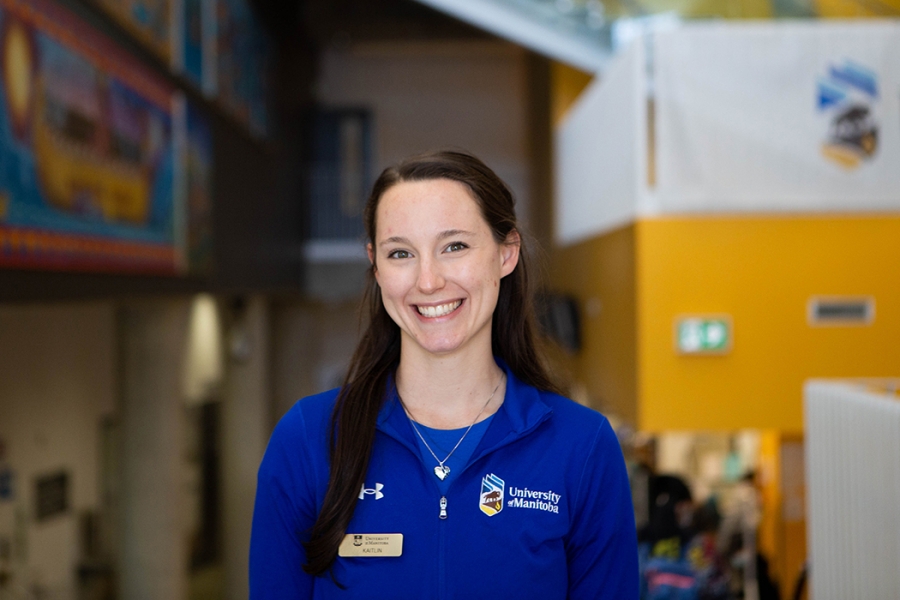 Kaitlin Reilly poses while wearing a University of Manitoba shirt and nametag.
