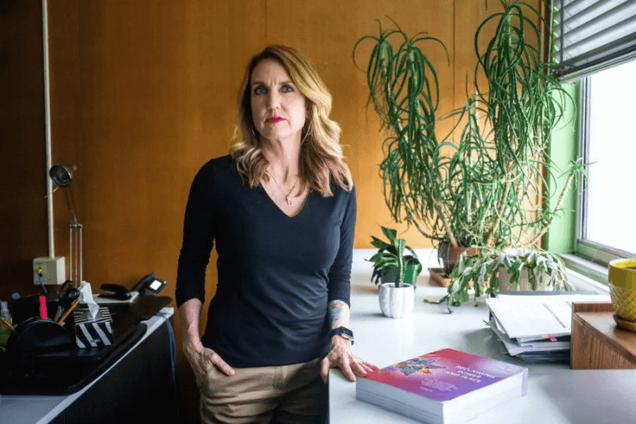 A blonde woman stands proudly at a counter (Dr. Kendra Nixon).