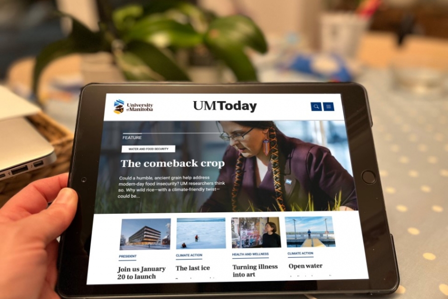 A person holding an ipad with the UM Today site displayed on the device.