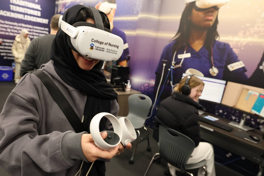 A woman holding controllers and wearing virtual reality goggles with a label reading College of Nursing.