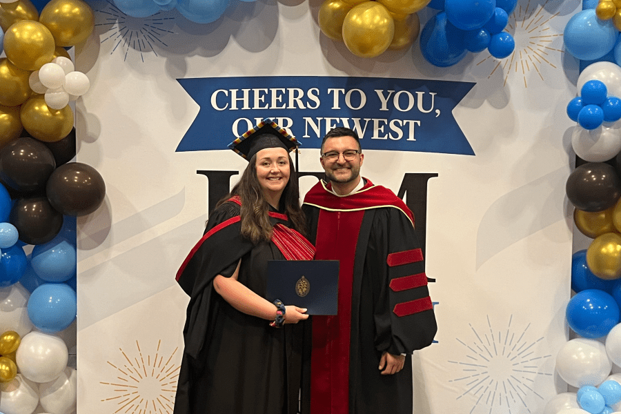Tara and advisor Dr. Rusty Souleymanov pose in front of UM convocation backdrop