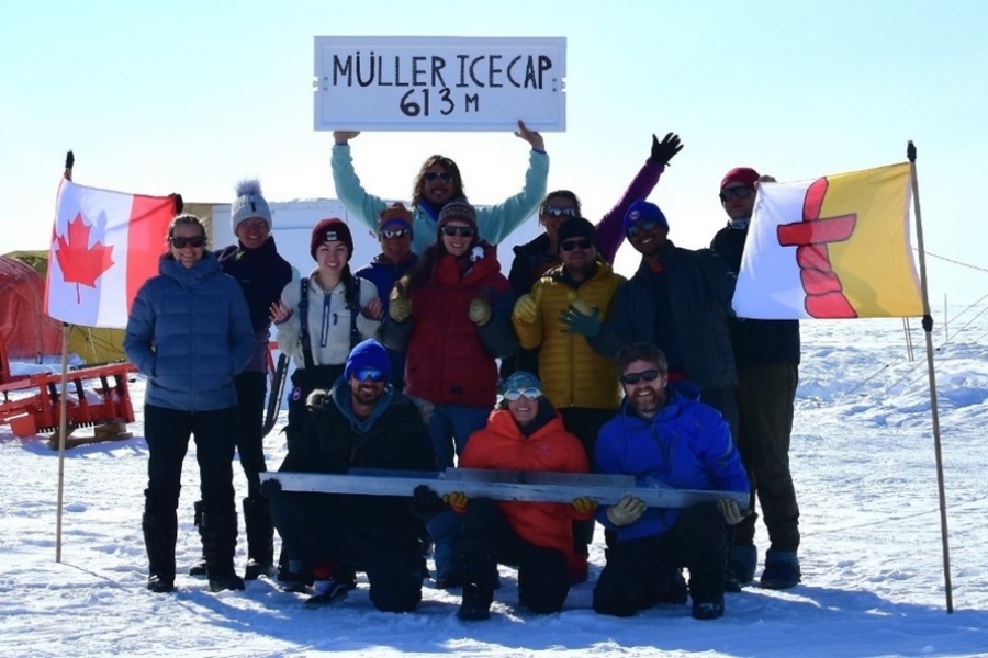 A group of scientists hold up Canadian and Manitoba flags in celebration of their ice core