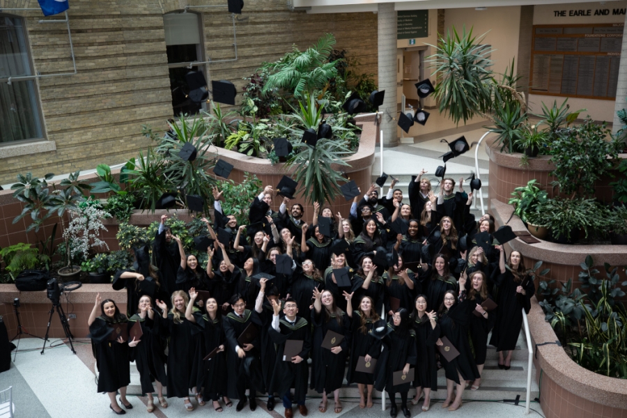 The group of graduates toss their caps in the air.