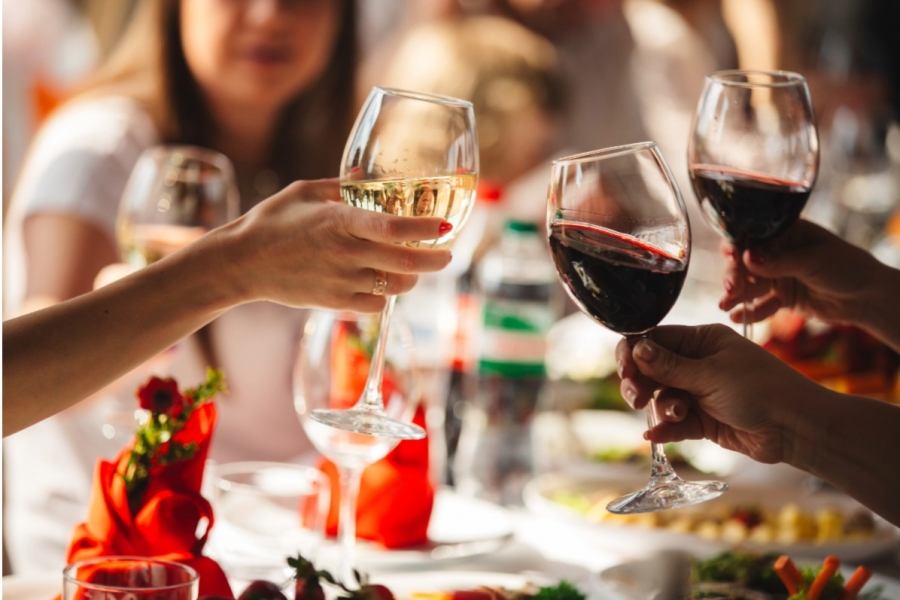 Hands lift wine glasses.