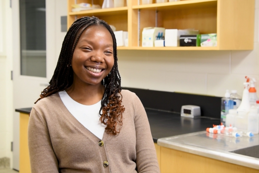 Dadiso Magadza wearing a brown cardigan in a lab smiling at the camera.