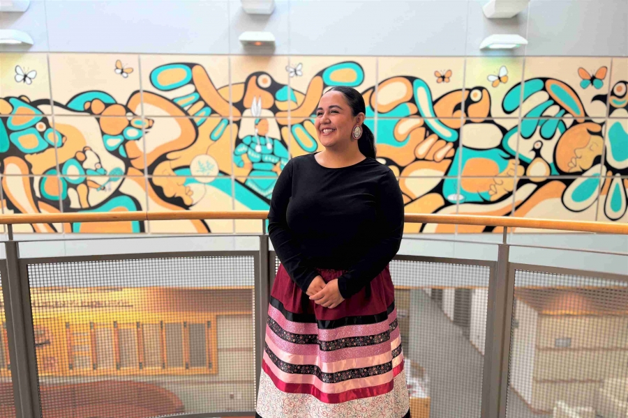 Woman wearing ribbon skirt stands proudly.