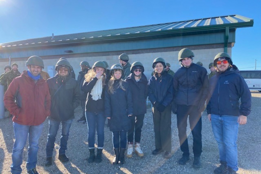 Group of eight students standing in a row, all wearing military helmets.