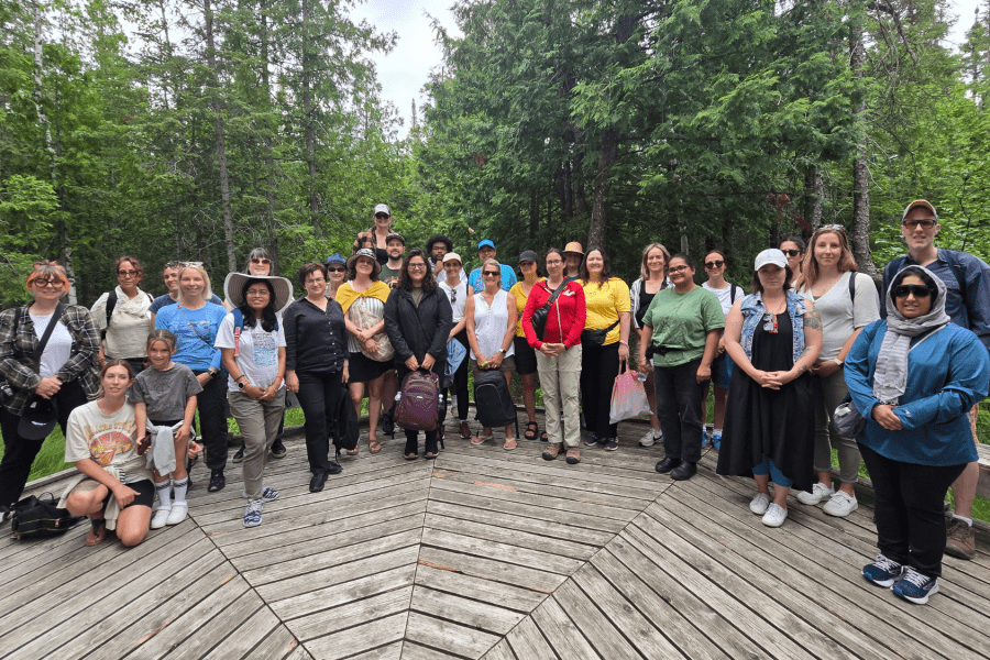 A group of Summer Institute participants posing for a photo on a wooden platform in the forest.