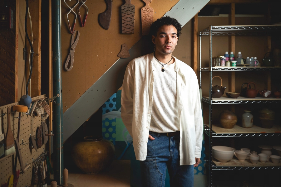 Joel Nichols stands in his basement art studio, surrounding by tools and ceramics
