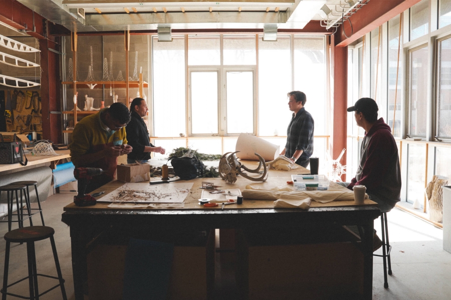 Stedents sit around a work bench talking