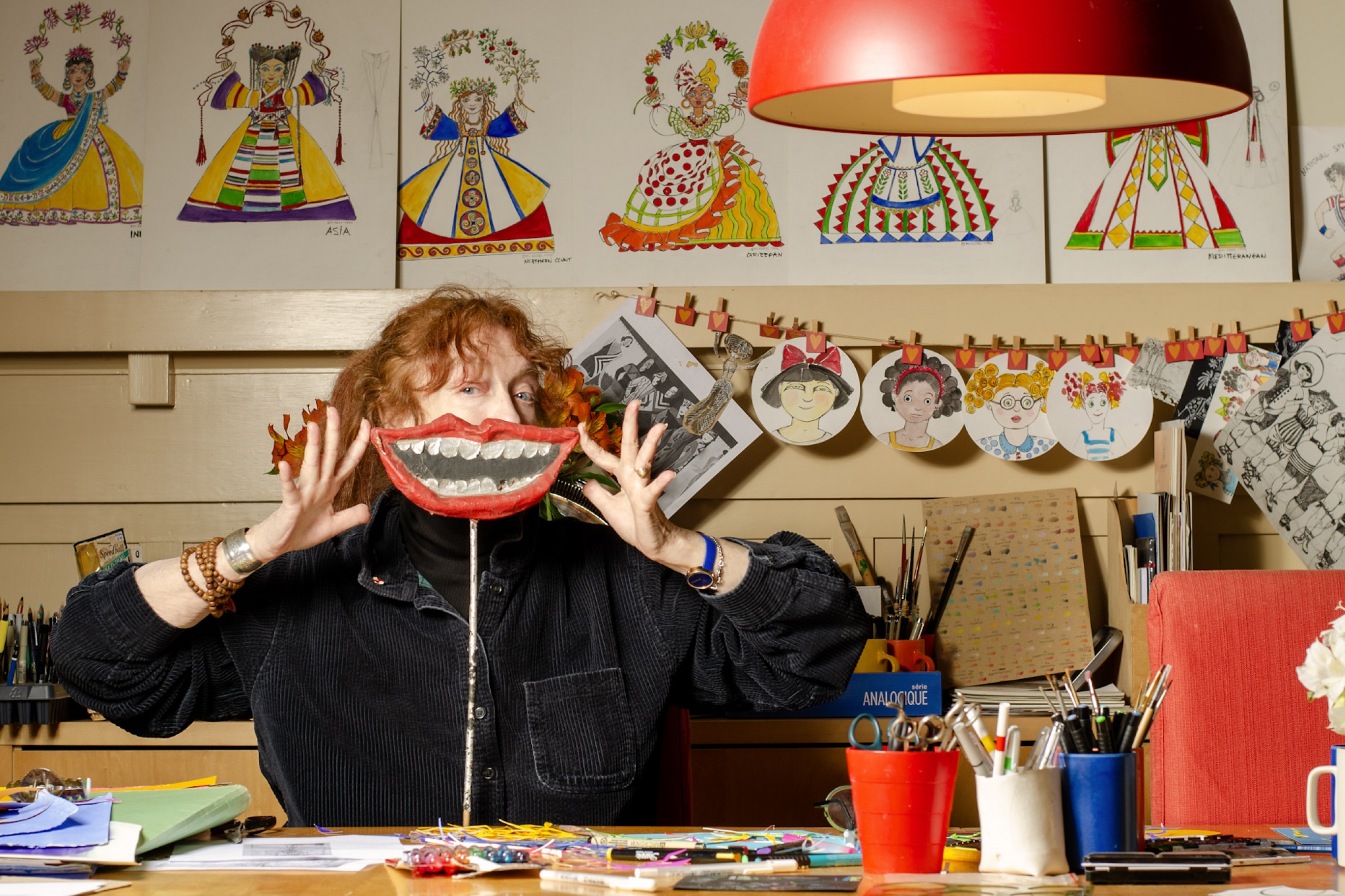 A woman holding a paper mache mouth in front of her own mouth