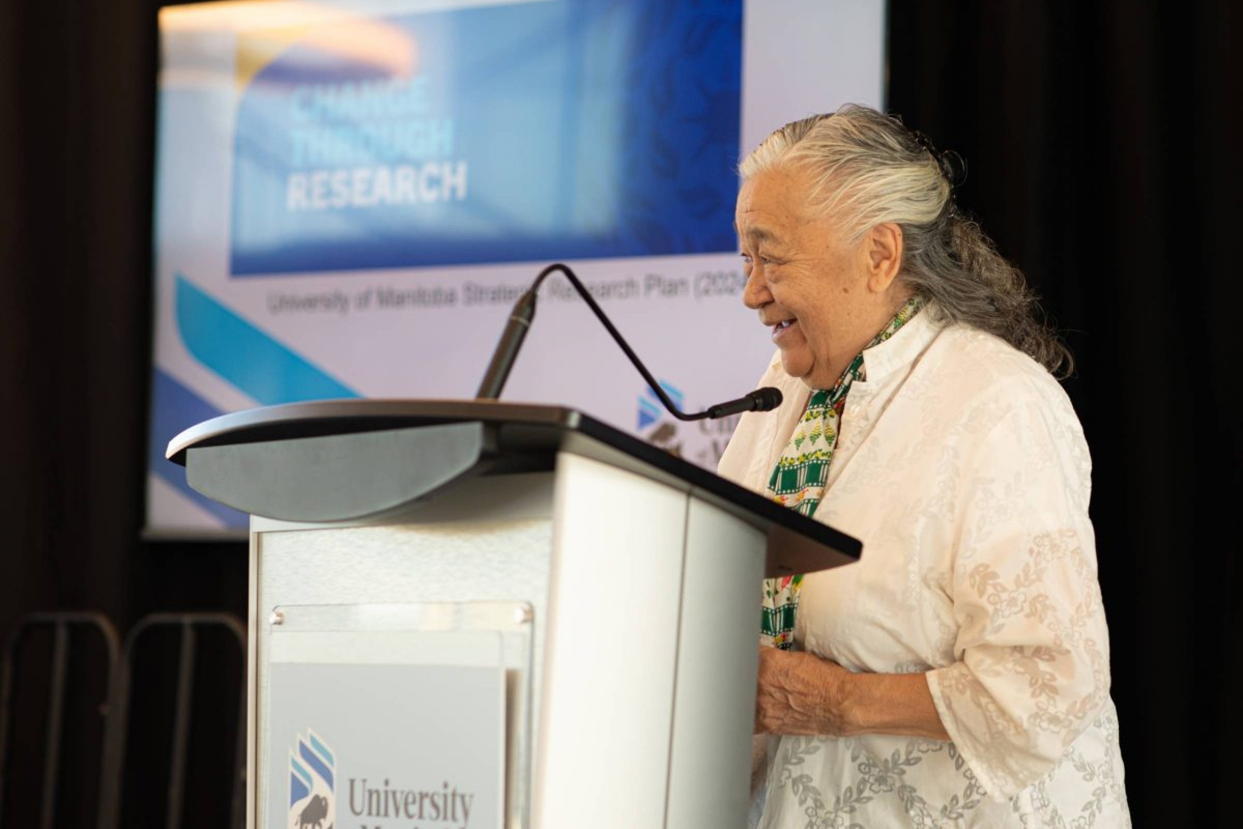 Elder Dr Levinia Brown stands at a podium addressing a crowd.
