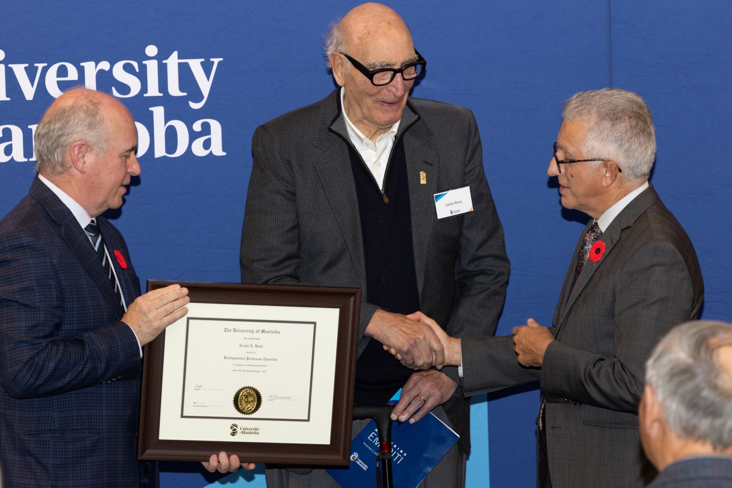 Chancellor Dave Angus and President Michael Benarroch present Leslie Roos with certificate for Distinguished Professor Emeritus.