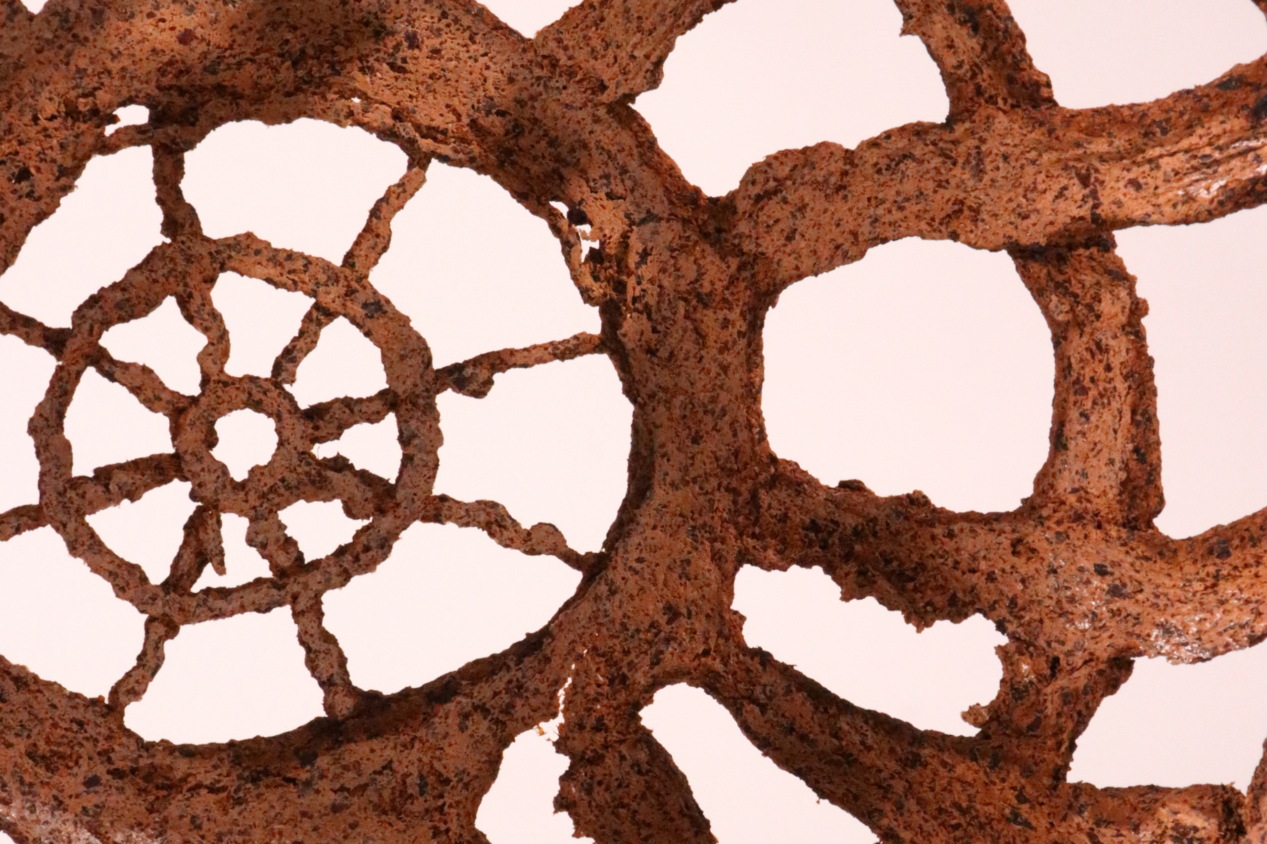 Close-up of a rusted metallic fan, resembling a geometric flower with intricate spokes.